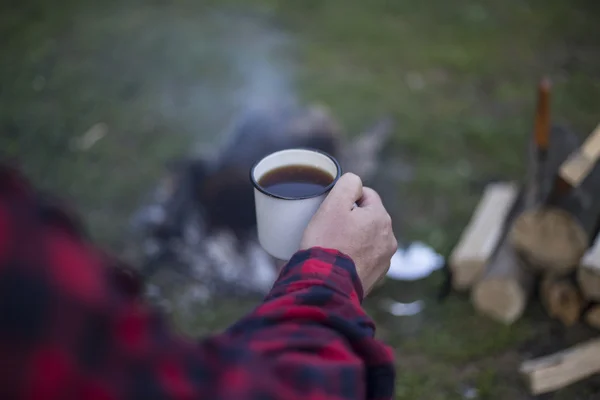 Hombre bebiendo café junto al fuego . — Foto de Stock