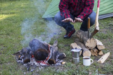 Adam bir çadır kampında yangın kahve hazırlar.