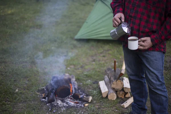 男は、テント キャンプで火にコーヒーを準備します。. — ストック写真