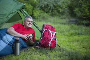 Çadırın oturan ve telefonda konuşurken bir adam.