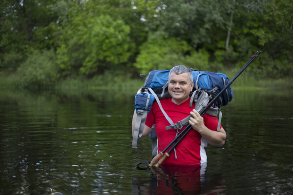 hiker man crossing the river to reach the other side