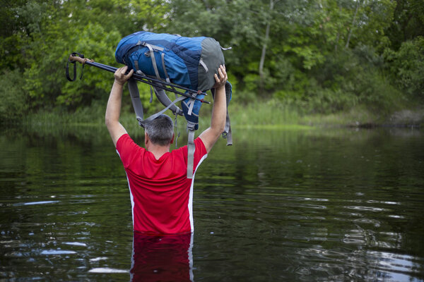 hiker man crossing the river to reach the other side