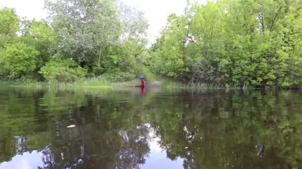 El viajero entra al río con una mochila en la mano . — Vídeo de stock