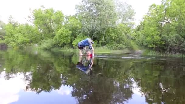 De reiziger komt de rivier met een rugzak in de hand. — Stockvideo