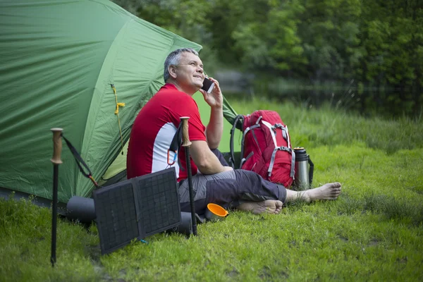 Der Mann sitzt neben Handyladungen von der Sonne. — Stockfoto