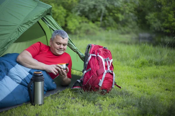 The man sitting next to mobile phone charges from the sun. — Stock Photo, Image