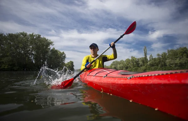 Un homme pagaie un kayak rouge . — Photo