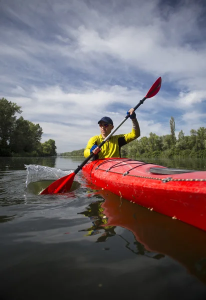 Un hombre remaba un kayak rojo . — Foto de Stock