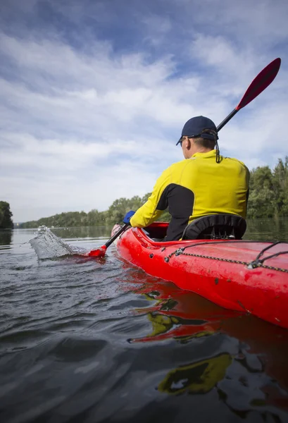 Un homme pagaie un kayak rouge . — Photo