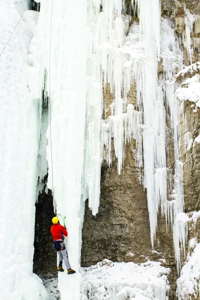 Eisklettern. Mann klettert gefrorenen Wasserfall. — Stockfoto