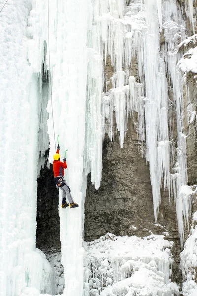 Ледолазание. Человек карабкается на замерзший водопад. . — стоковое фото