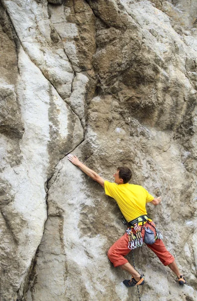 Cliffhanger.Young manliga klättrare hängande av en klippa. — Stockfoto