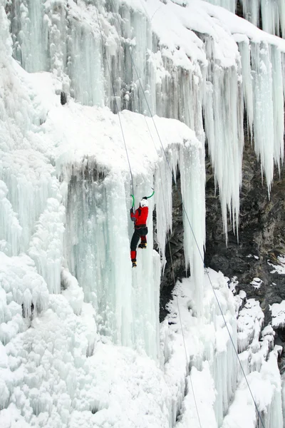 Man klättring frusna vattenfall — Stockfoto