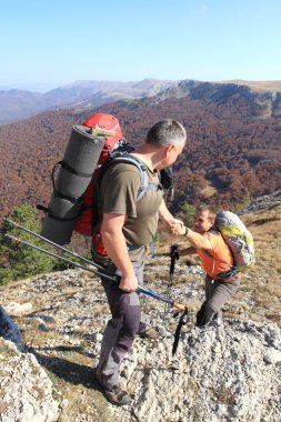 Dağ taş cliff tırmanmaya arkadaşına yardım elini veren adam