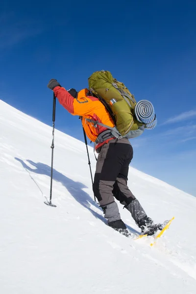 Senderismo de invierno en las montañas en raquetas de nieve con una mochila y tienda de campaña . — Foto de Stock