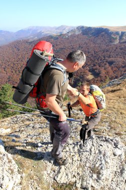 Dağ taş cliff tırmanmaya arkadaşına yardım elini veren adam.