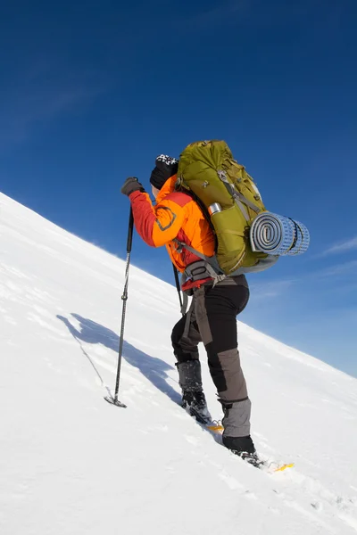 Caminhadas de inverno nas montanhas em sapatos de neve com uma mochila e tenda . — Fotografia de Stock