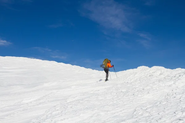 Vinter vandring i bergen på snöskor med en ryggsäck och tält. — Stockfoto