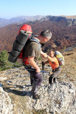 Dağ taş cliff tırmanmaya arkadaşına yardım elini veren adam.