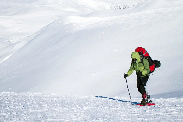 Vinter vandring i bergen på snöskor med en ryggsäck och tält. — Stockfoto