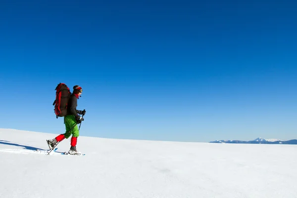 Vinter vandring i bergen på snöskor med en ryggsäck och tält. — Stockfoto