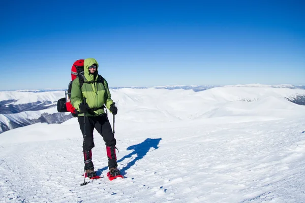 Winter hiking in the mountains on snowshoes with a backpack and tent. — Stock Photo, Image