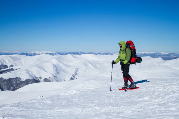 Winter wandelen in de bergen op sneeuwschoenen met een rugzak en tent. — Stockfoto