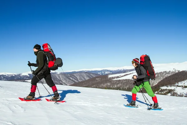 Caminhadas de inverno nas montanhas em sapatos de neve com uma mochila e tenda . — Fotografia de Stock