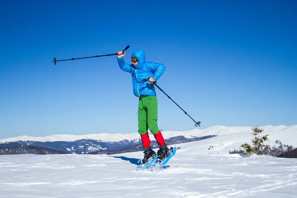 Genç adam güzel bir karlı bir kış günü açık havada snowshoeing yaparken eğlenmek. — Stok fotoğraf