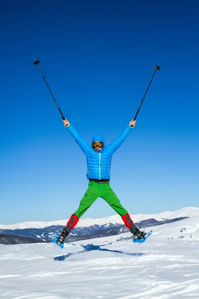 Junger Mann hat Spaß beim Schneeschuhwandern im Freien an einem schönen verschneiten Wintertag. — Stockfoto