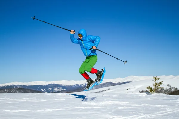 Junger Mann hat Spaß beim Schneeschuhwandern im Freien an einem schönen verschneiten Wintertag. — Stockfoto