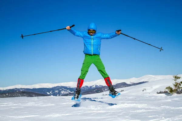 Junger Mann hat Spaß beim Schneeschuhwandern im Freien an einem schönen verschneiten Wintertag. — Stockfoto