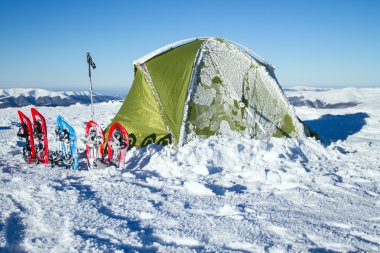 Çadır kış dağlar. Karda dağlarda çadır duruyor. Kar ayakkabılarını çadır vardır.