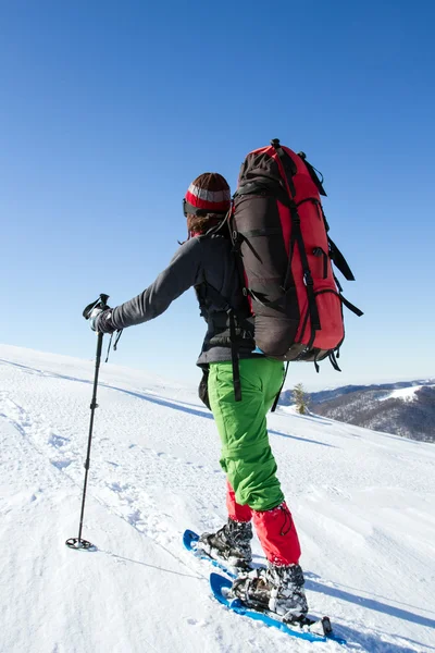 Senderismo de invierno en las montañas en raquetas de nieve con una mochila y tienda de campaña . — Foto de Stock