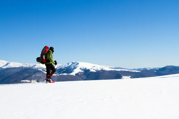Winter wandelen in de bergen op sneeuwschoenen met een rugzak en tent. — Stockfoto