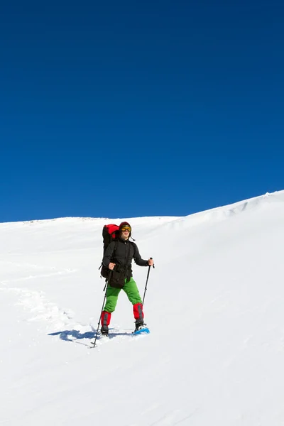 Vinter vandring i bergen på snöskor med en ryggsäck och tält. — Stockfoto