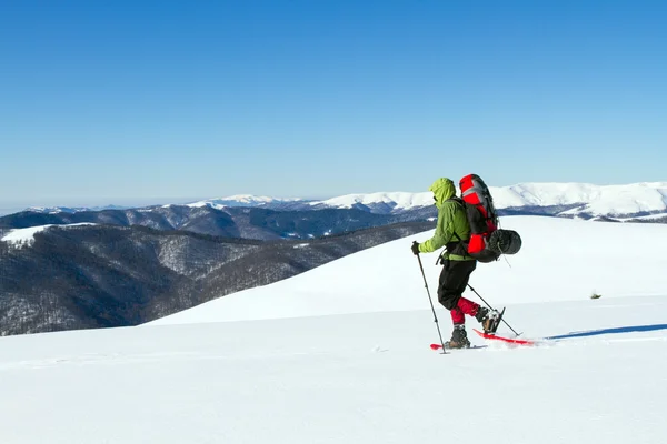 Caminhadas de inverno nas montanhas em sapatos de neve com uma mochila e tenda . — Fotografia de Stock