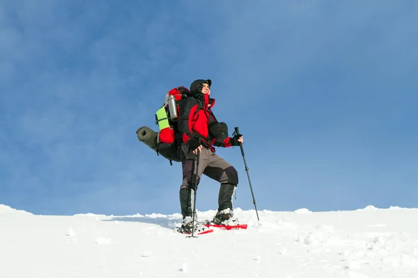 Téli túrázás a hegyekben a hótalp hátizsák és sátor. — Stock Fotó