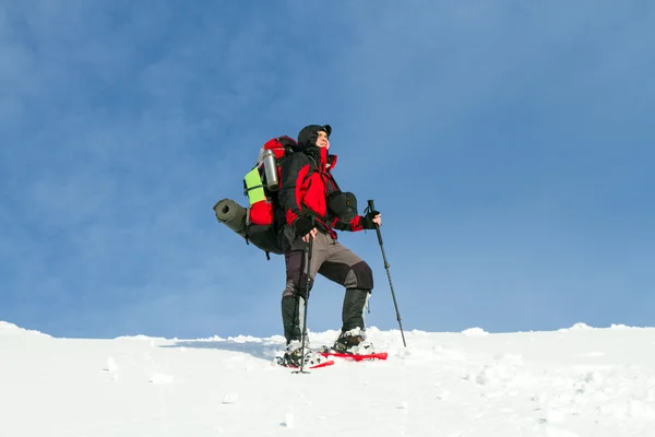 Caminhadas de inverno nas montanhas em sapatos de neve com uma mochila e tenda . — Fotografia de Stock