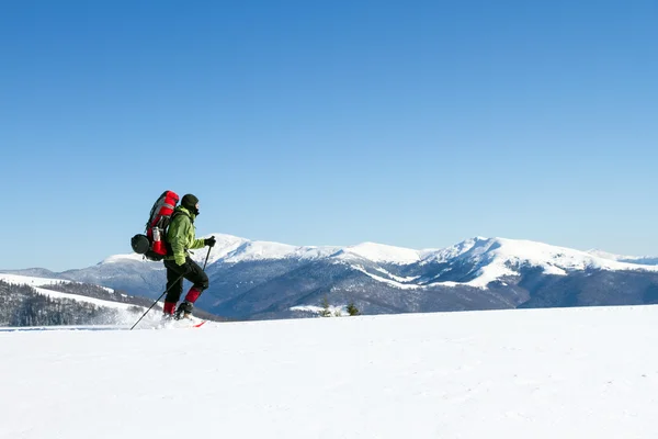 Caminhadas de inverno nas montanhas em sapatos de neve com uma mochila e tenda . — Fotografia de Stock
