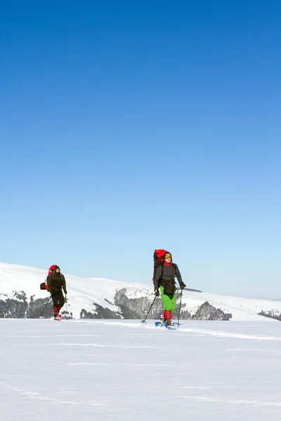 Senderismo de invierno en las montañas en raquetas de nieve con una mochila y tienda de campaña . — Foto de Stock