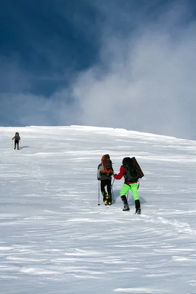 Senderismo de invierno en las montañas en raquetas de nieve con una mochila y tienda de campaña . — Foto de Stock