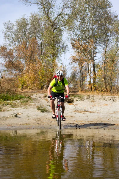 Young athlete crossing rocky terrain with bicycle in his hands. — Stock Photo, Image