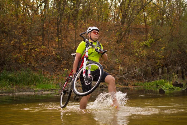 Giovane atleta attraversando terreno roccioso con bicicletta nelle sue mani.bi — Foto Stock