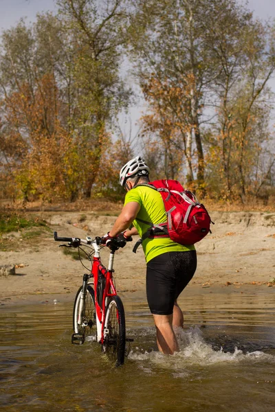 Young athlete crossing rocky terrain with bicycle in his hands. — Stock Photo, Image