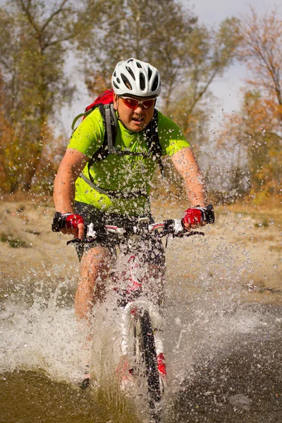 Junger Sportler überquert felsiges Gelände mit Fahrrad in der Hand. — Stockfoto