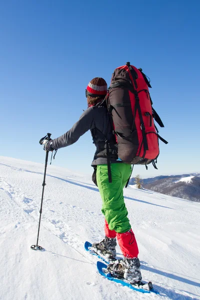 Vinter vandring i bergen på snöskor med en ryggsäck och tält. — Stockfoto