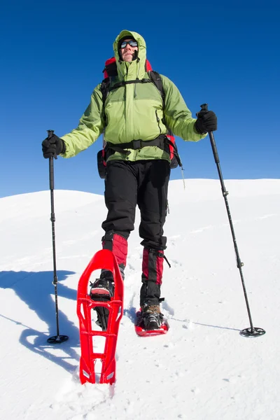 Senderismo de invierno en las montañas en raquetas de nieve con una mochila y tienda de campaña . — Foto de Stock