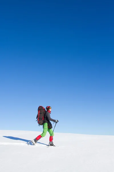 Senderismo de invierno en las montañas en raquetas de nieve con una mochila y tienda de campaña . — Foto de Stock