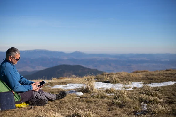 The solar panel attached to the tent. The man sitting next to mobile phone charges from the sun. — Stock Photo, Image